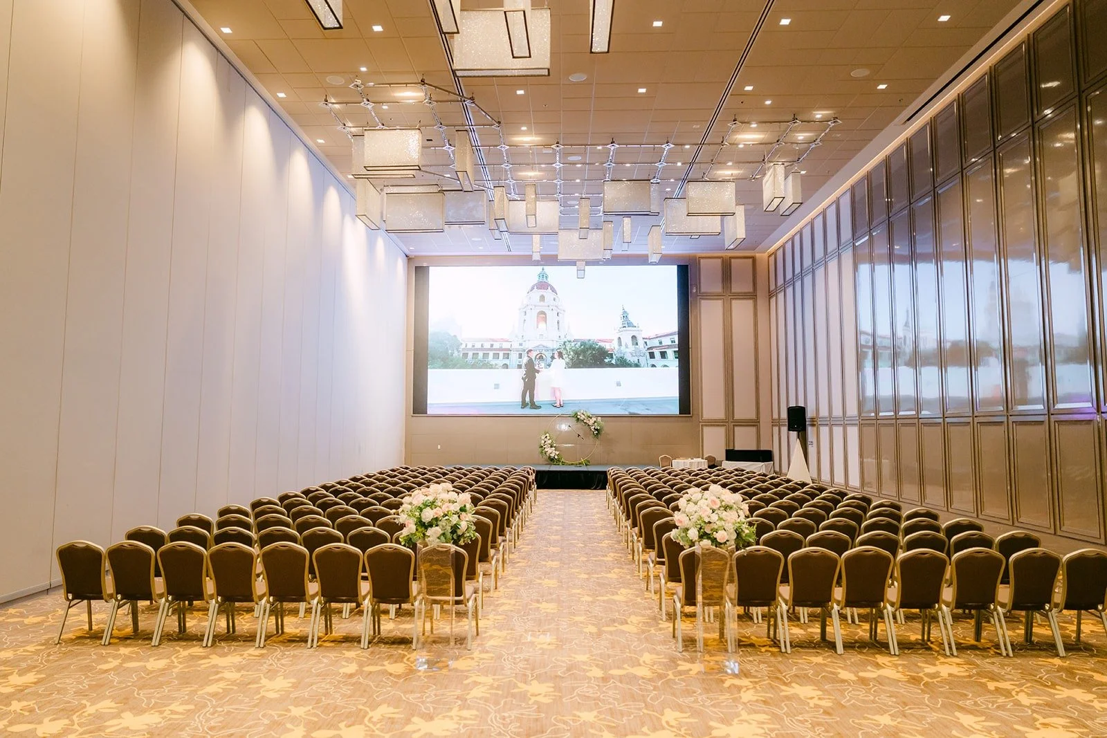 The ballroom at the Sheraton Los Angeles San Gabriel set for the ceremony with rows of chairs and a large screen