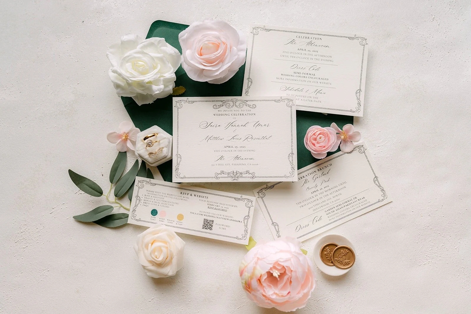 The invitation suite laid out on a dark green envelope with blush and white roses