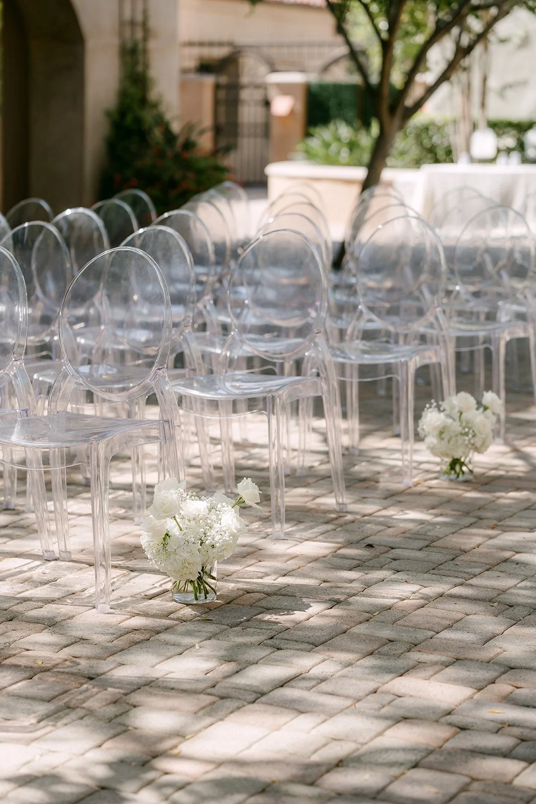 Baby's breath aisle markers on ghost chairs in the courtyard