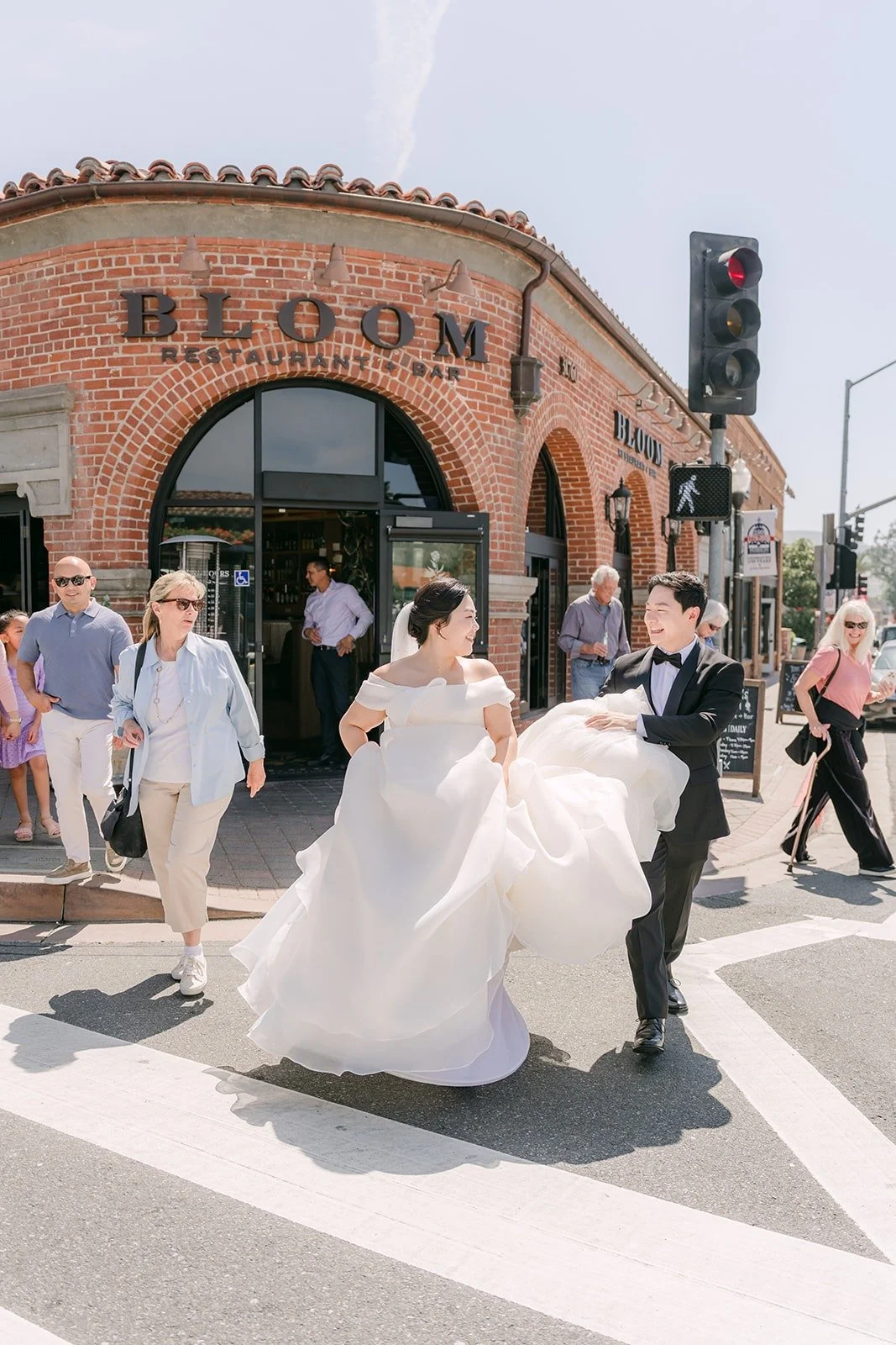 Chorok and Min Soo crossing the street in San Juan Capistrano, her gown lifted in her hands