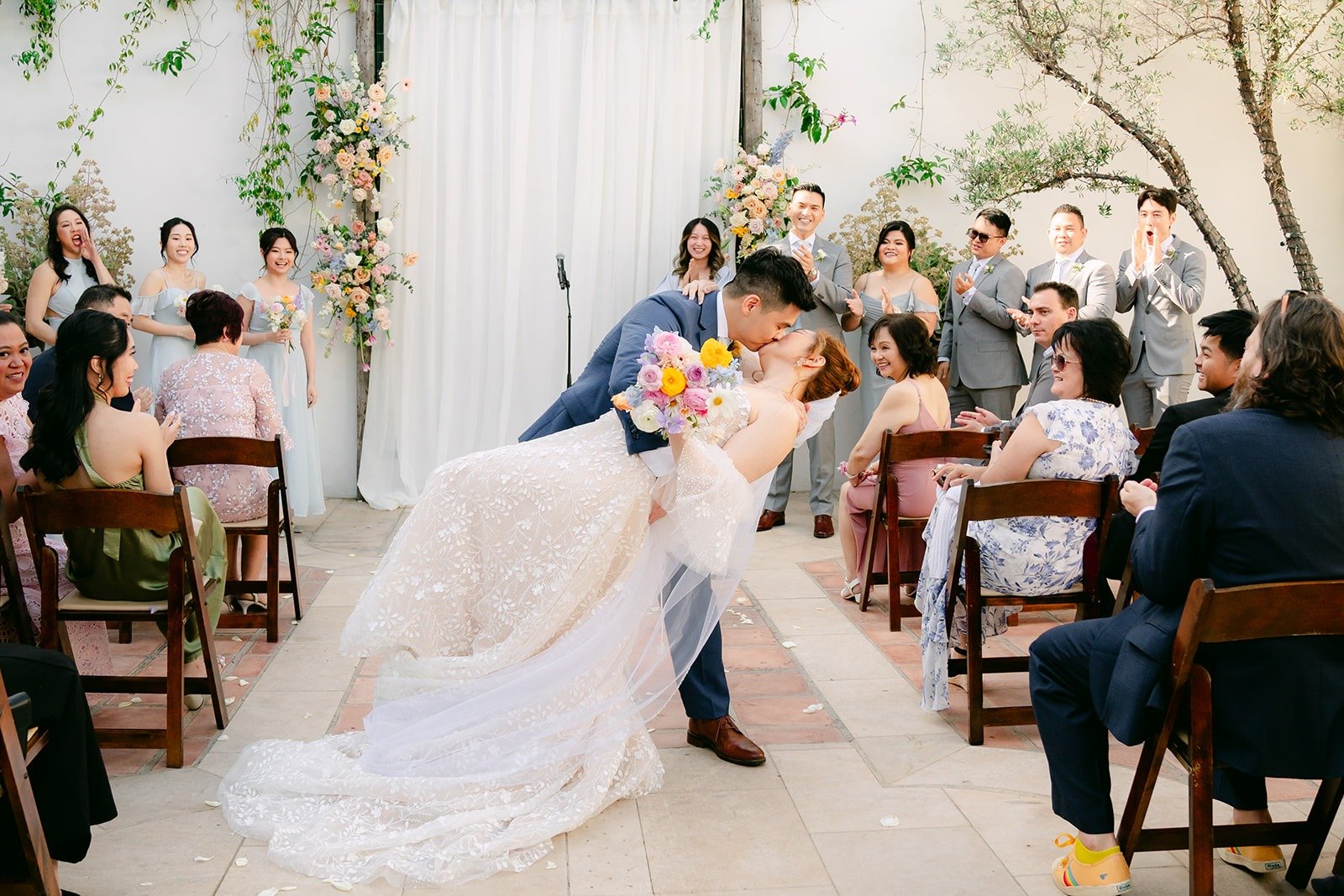 Jerrick dipping Joanna for their first kiss as guests cheer, photographed by One and Only Production