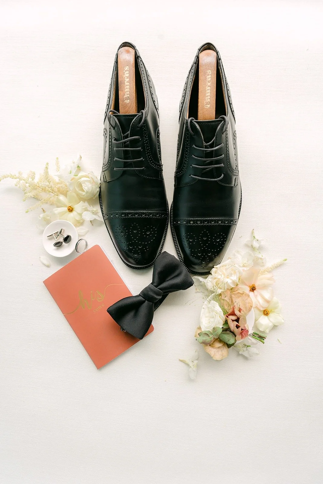 Eli's black dress shoes, bow tie and boutonniere on the flat lay