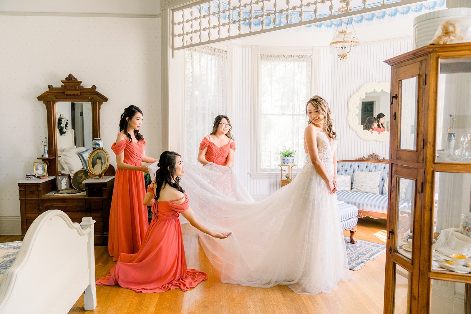 A bridesmaid helping Ariel with her gown, photographed by One and Only Production