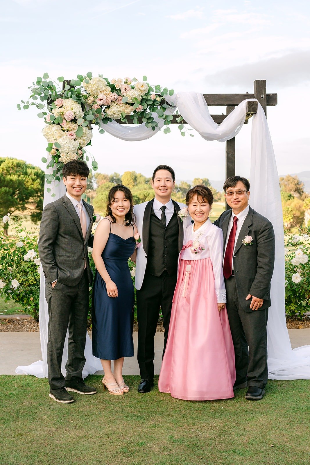 Ivy and Chungman with family under the floral arch