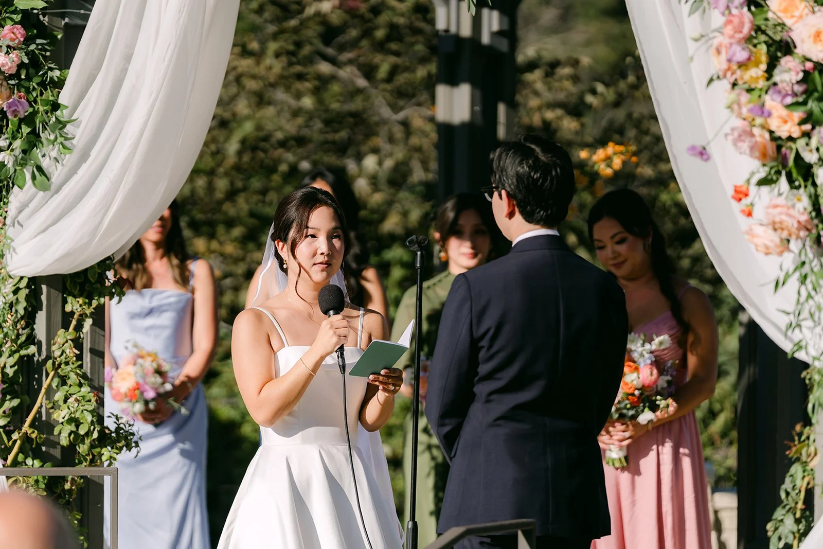 Saya reading her vows under the garden arch