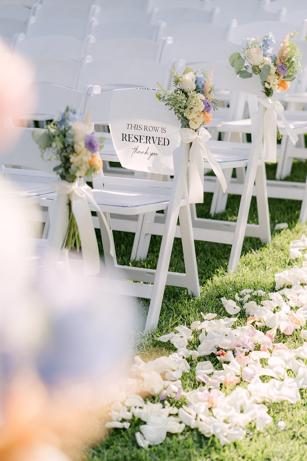 White chairs lining an aisle scattered with petals