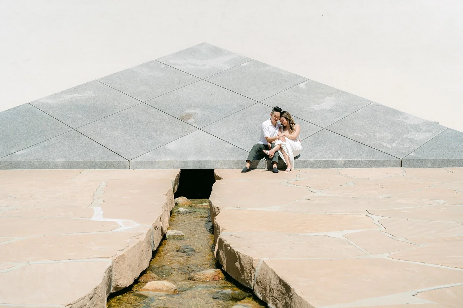Wide view of Stephanie and Alan seated at the pyramid above the stream.