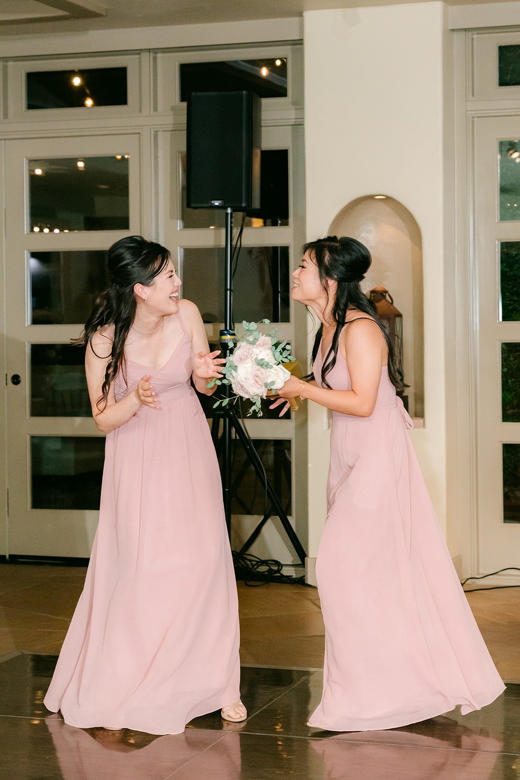 Two bridesmaids dancing into the ballroom