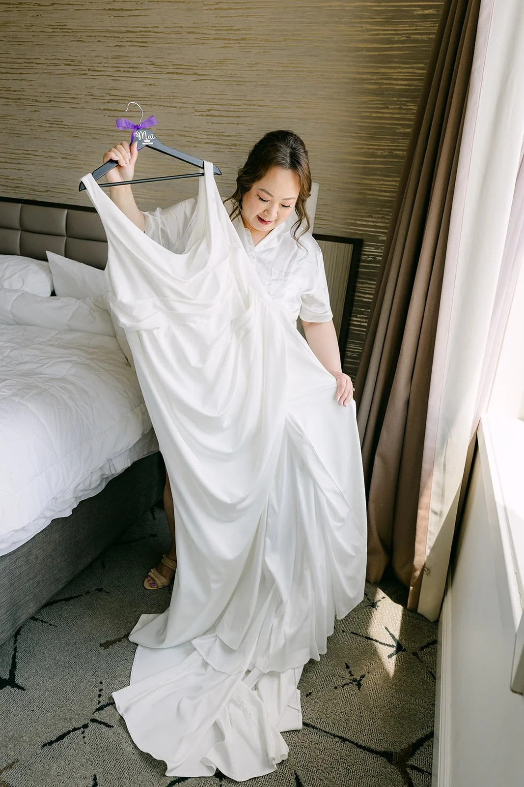 Mai holding up her gown in the bridal suite.