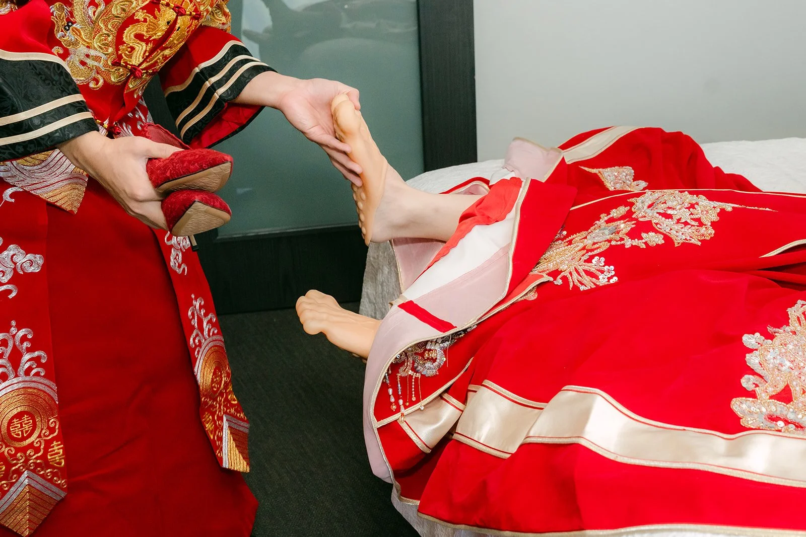 The groom slipping the bride's red shoe onto her foot after the door game.