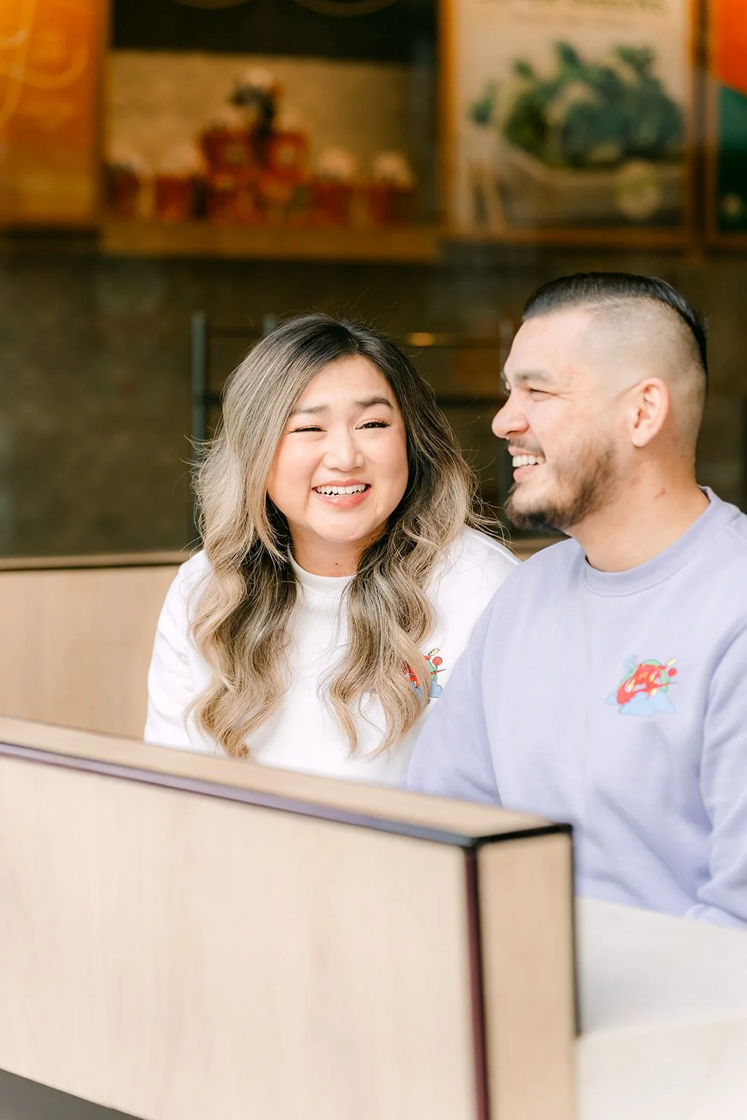 Linh and Ankush smiling together in a booth.