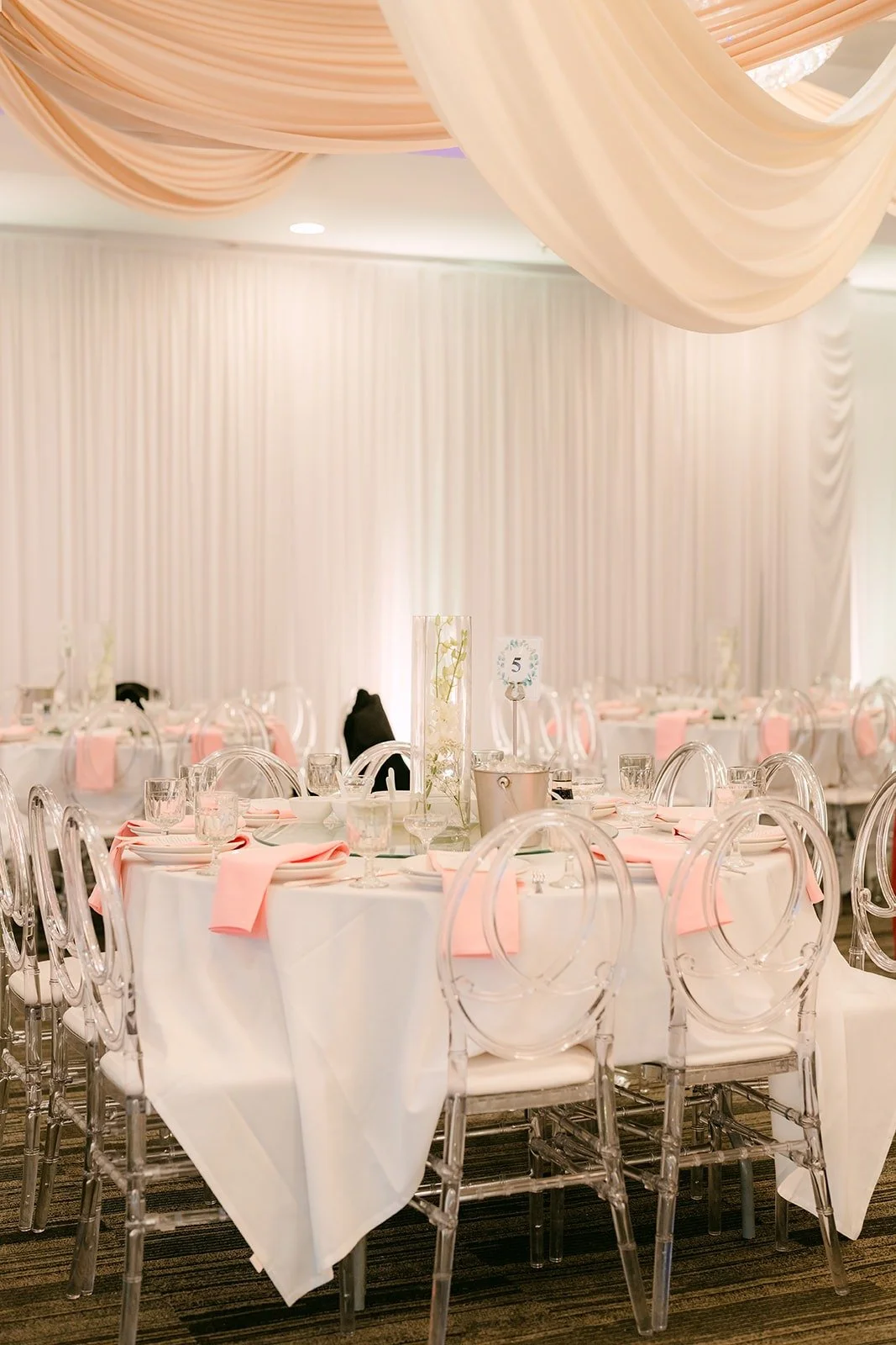 Guest tables set with blush napkins and white chiavari chairs