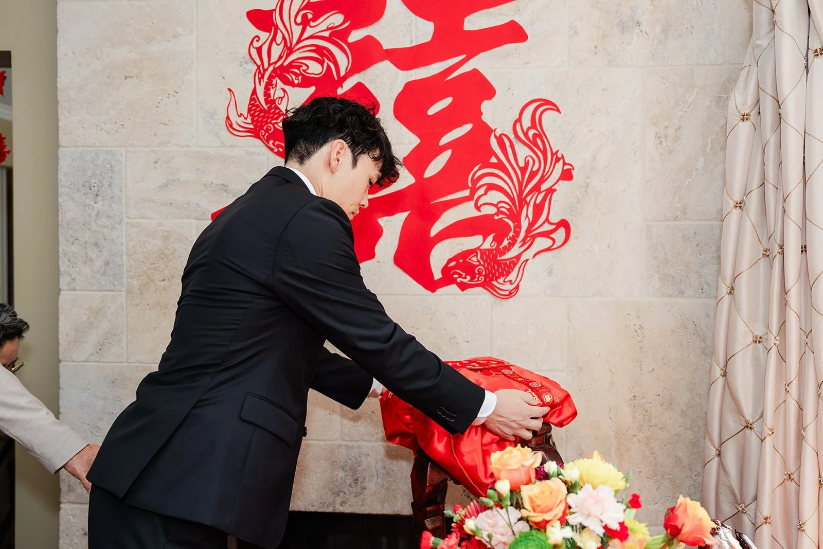 The groom placing a red gift tray beneath a double happiness papercut.