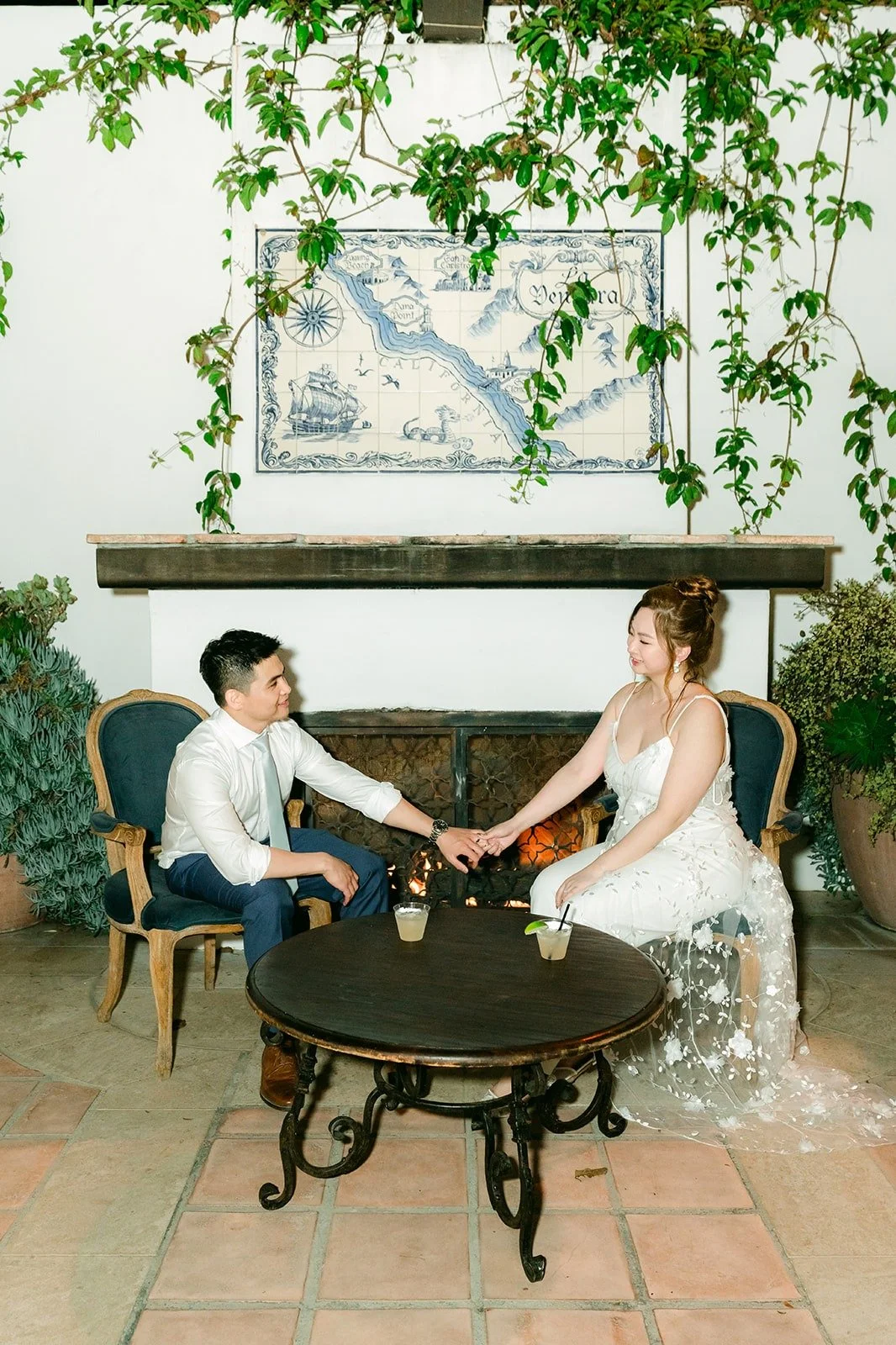 Joanna and Jerrick sitting at a small table beside a painted tile mural