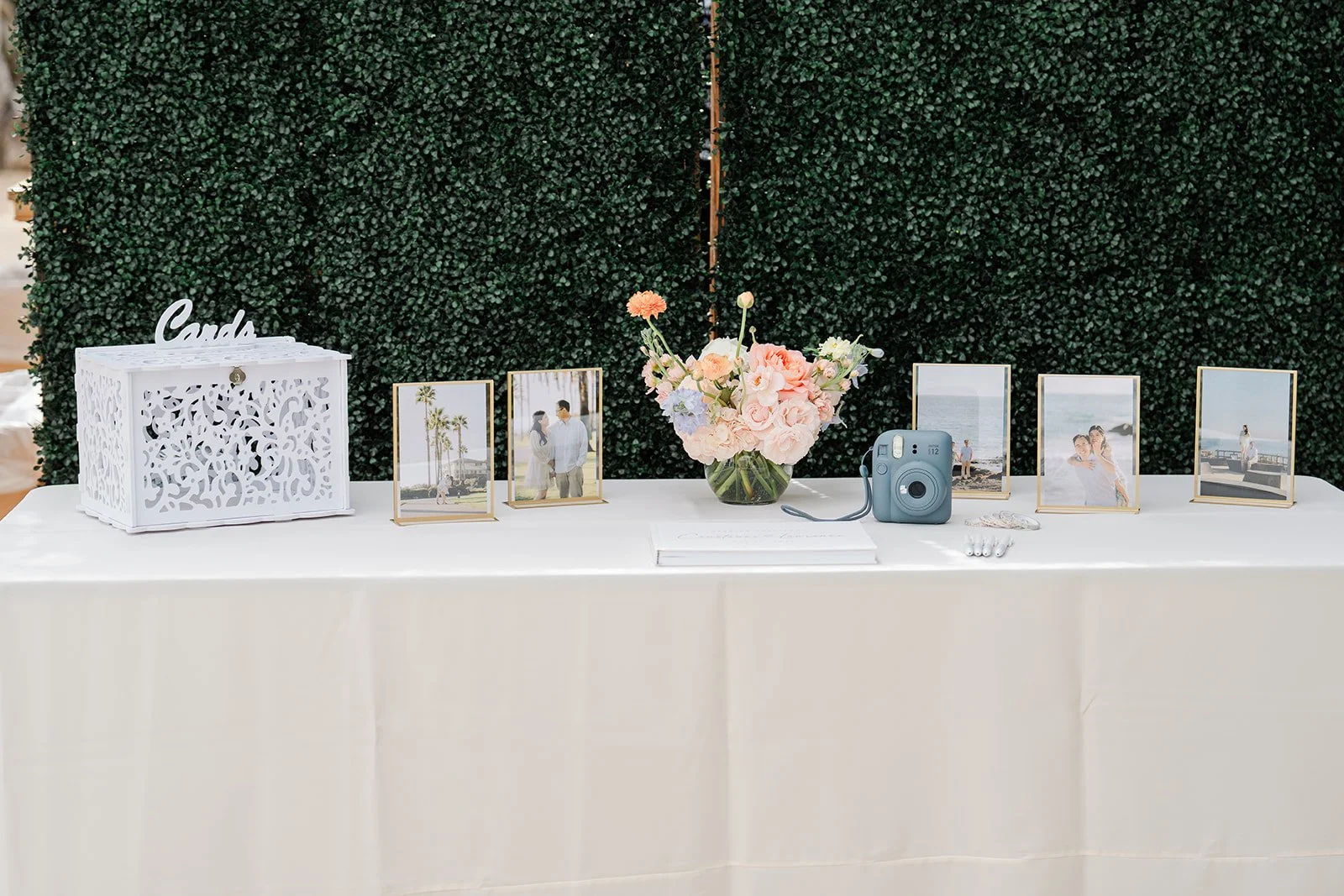 Welcome and card table set against a green hedge wall