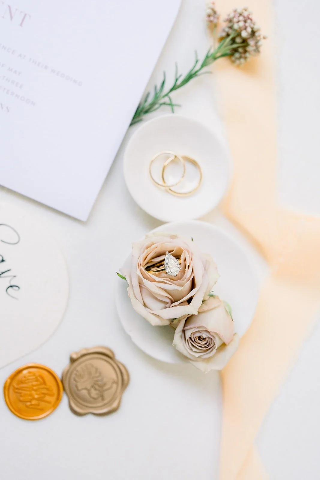 Rings resting on dried roses beside peach silk ribbon