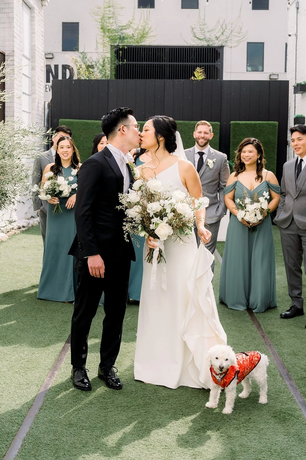 Alex kisses Cindy's cheek in front of their wedding party