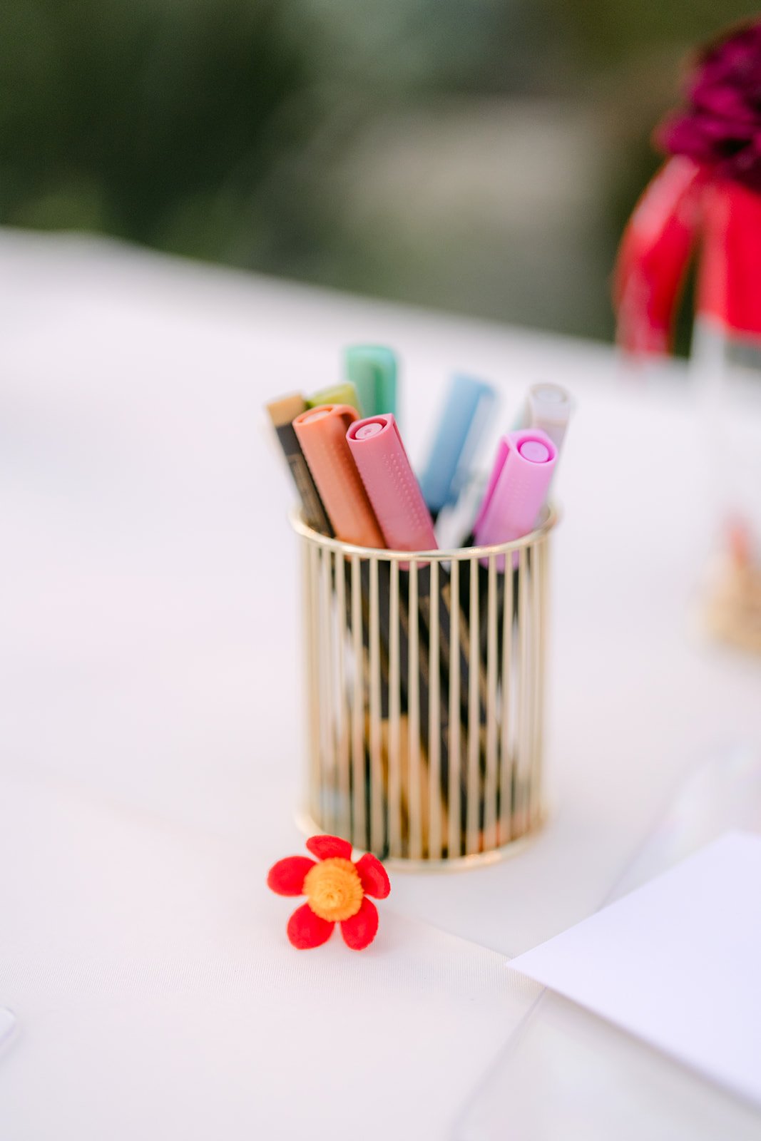 A cup of pens with one of Elaine's handmade red flowers.