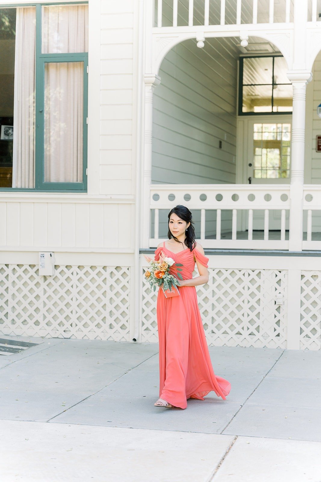 A bridesmaid in coral walking down the aisle