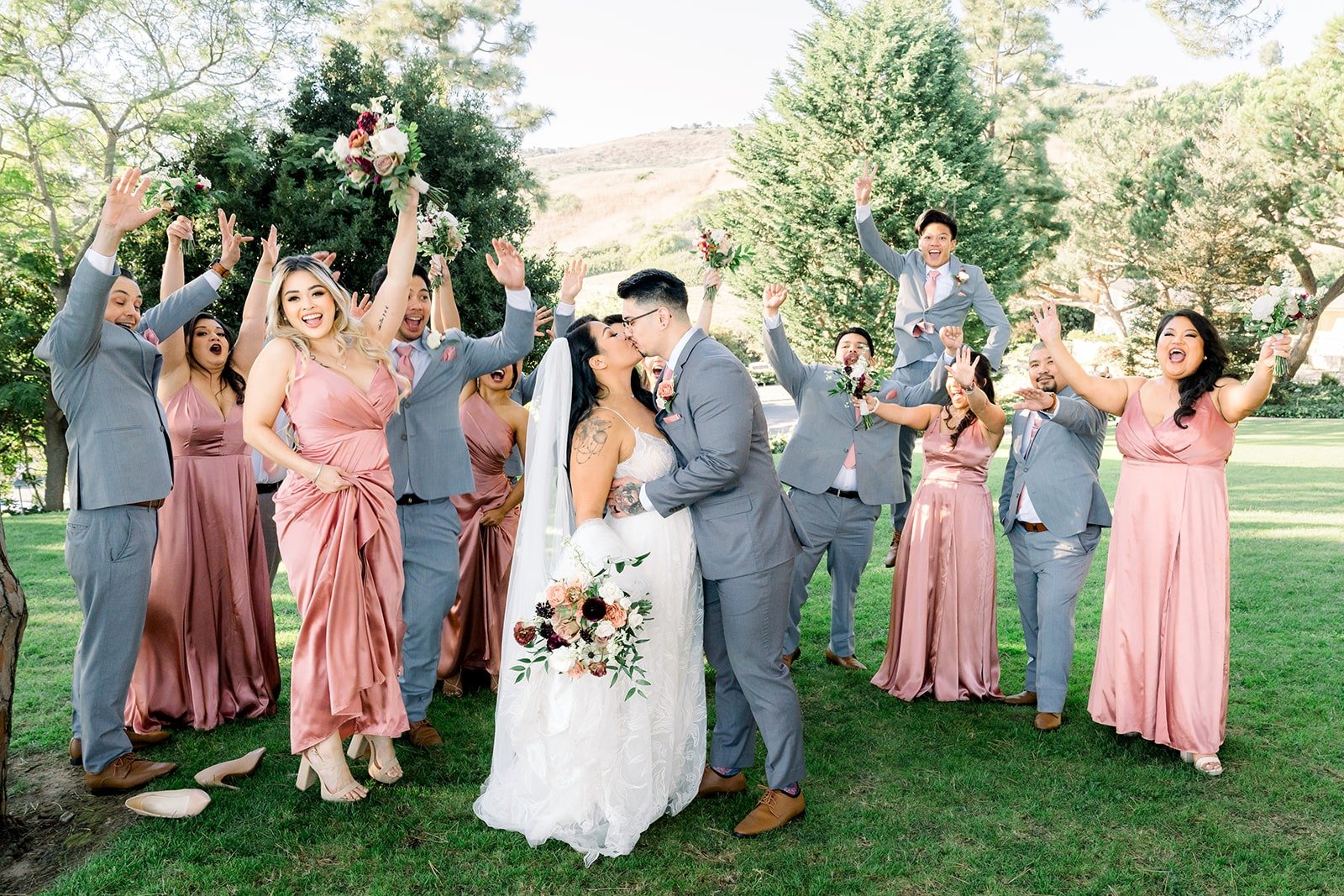 The wedding party celebrates with bouquets in the air, photographed by One and Only Production