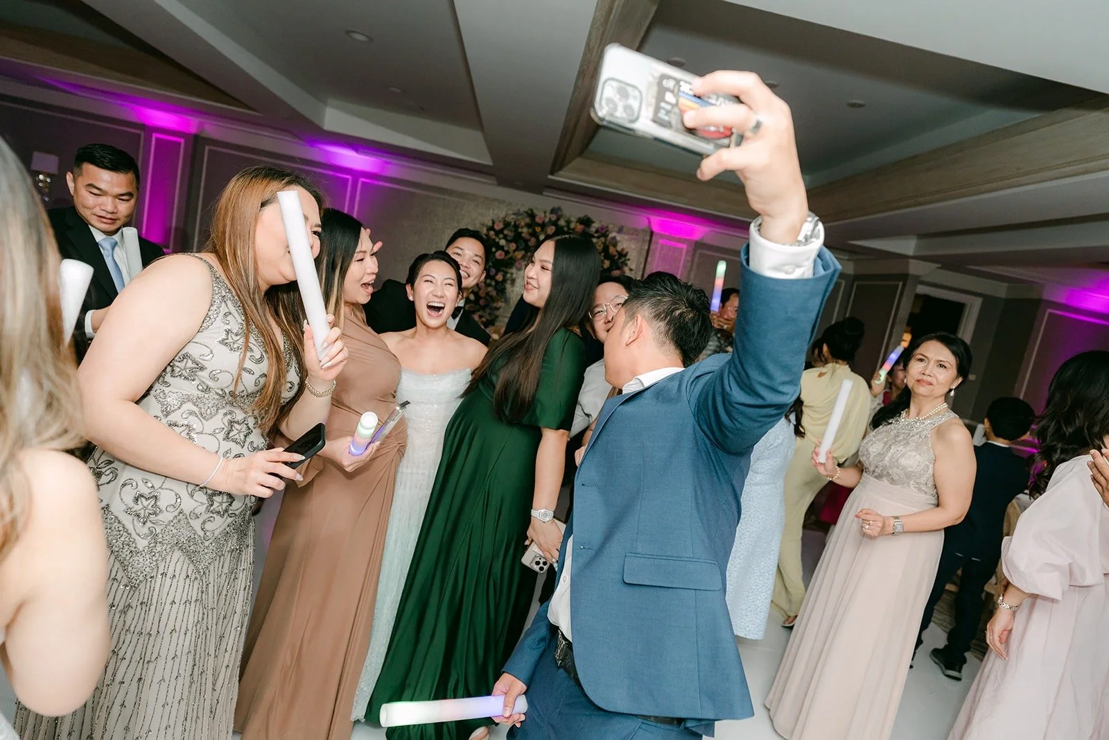 A guest taking a selfie with the dancing crowd behind him