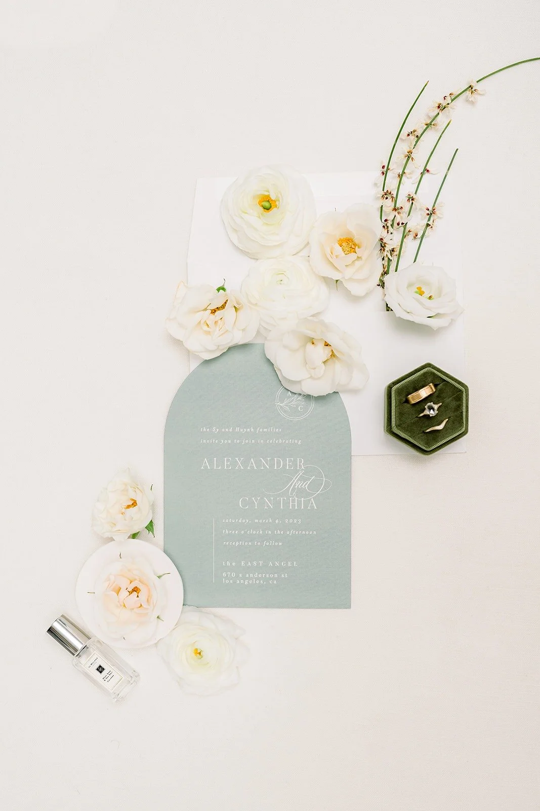 Sage green invitation styled with white flowers and the ring box