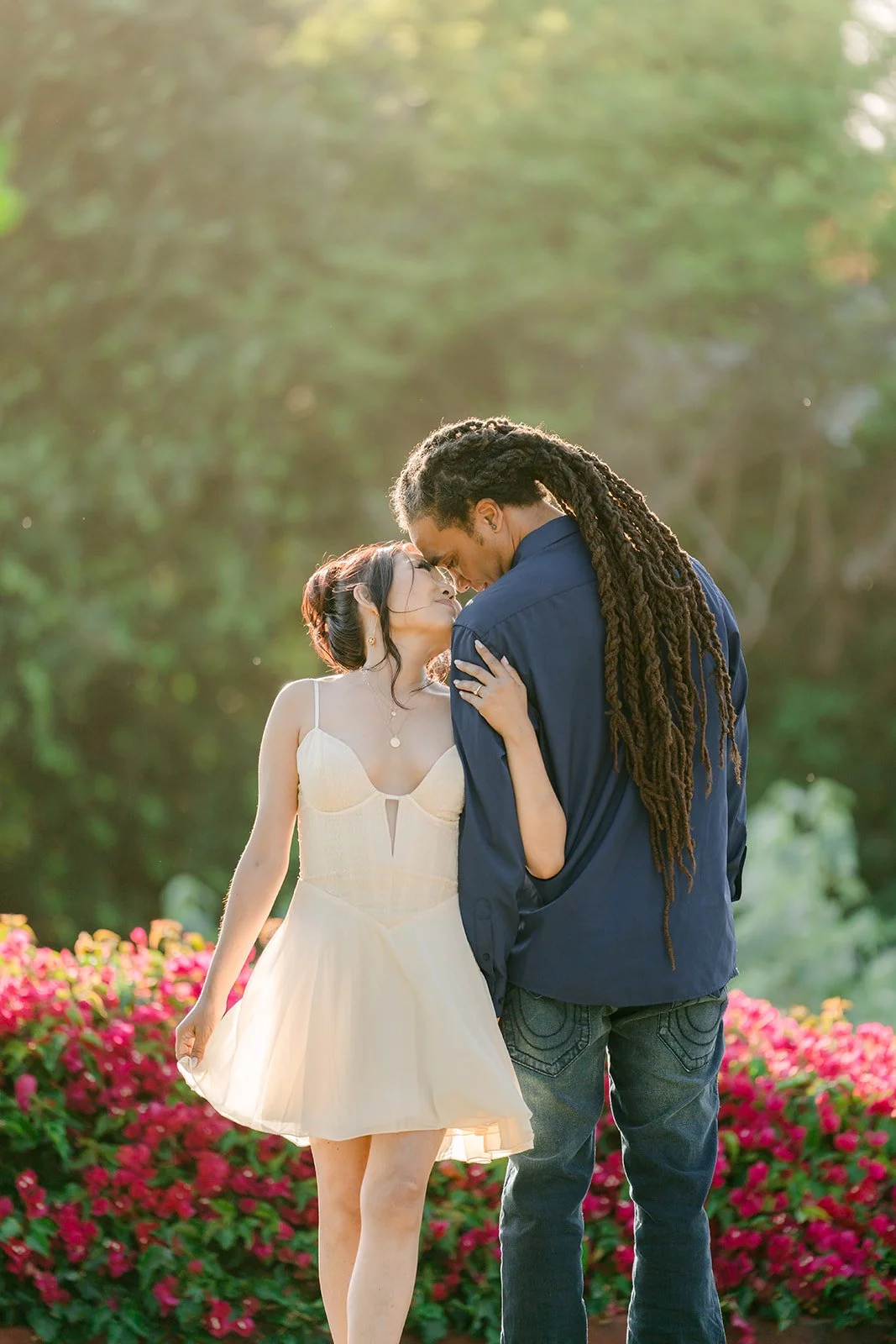 Michael kissing Amy's cheek in front of the flowers.