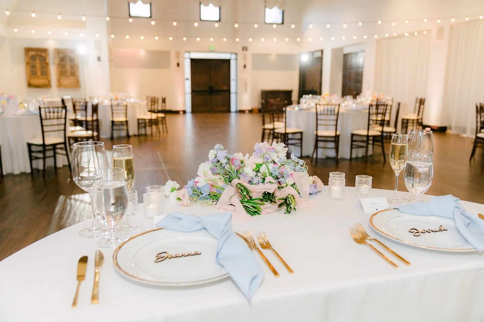 Round tables set with dusty blue napkins in the parlor