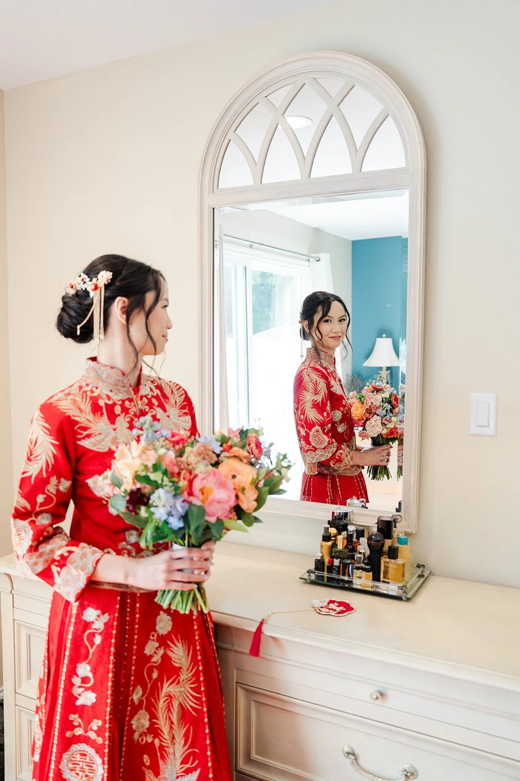 Bridgette in her qun kwa by an arched mirror.