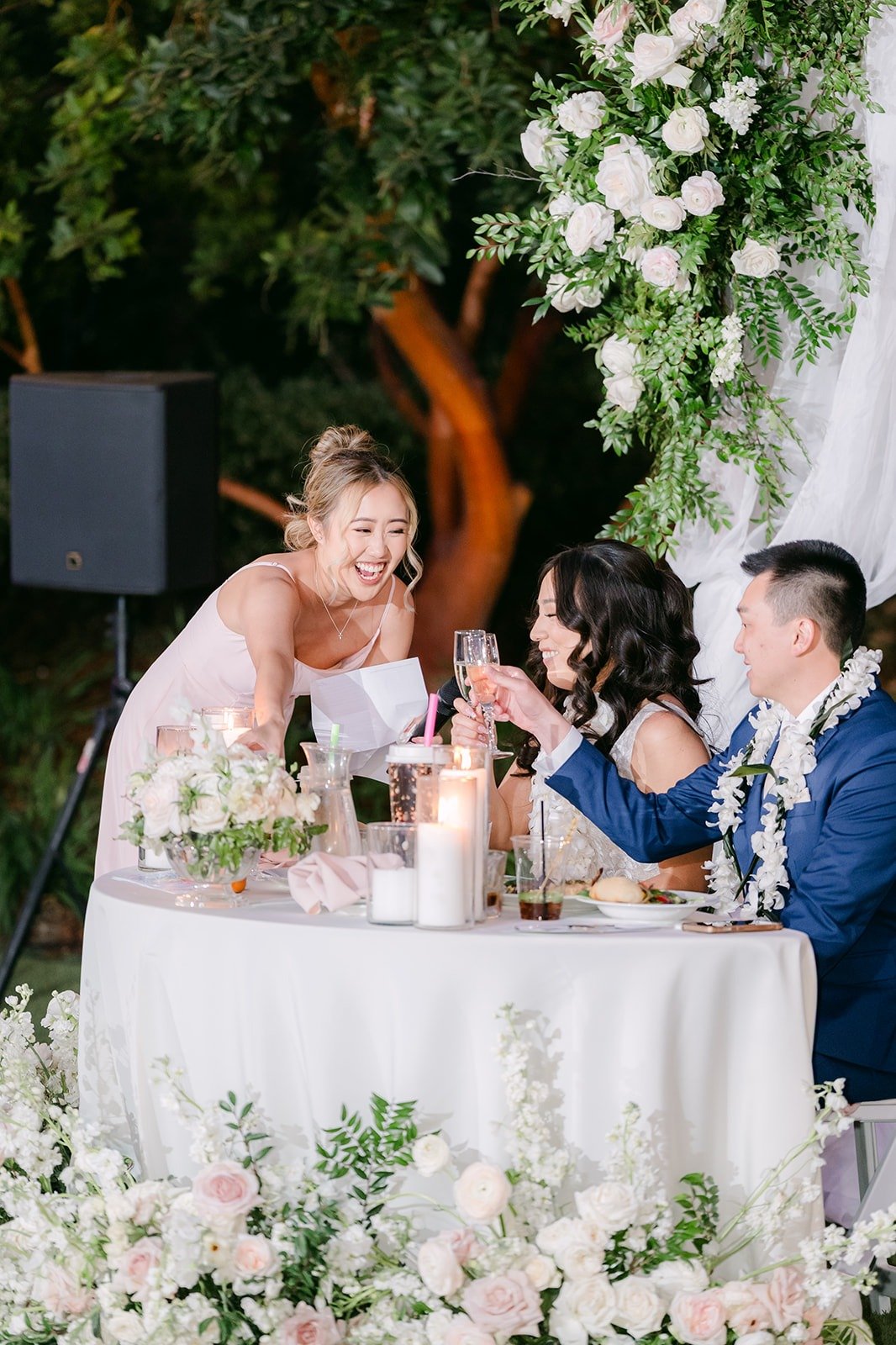 Kelli and Alex laughing at the sweetheart table during the toasts