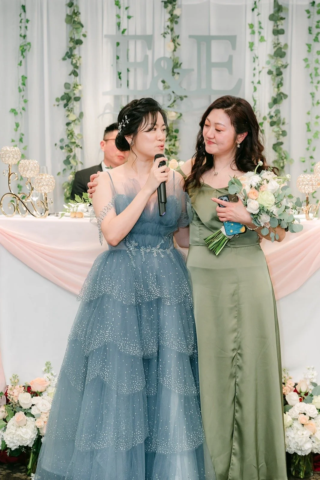 Eunice presents her bouquet to a bridesmaid in olive green