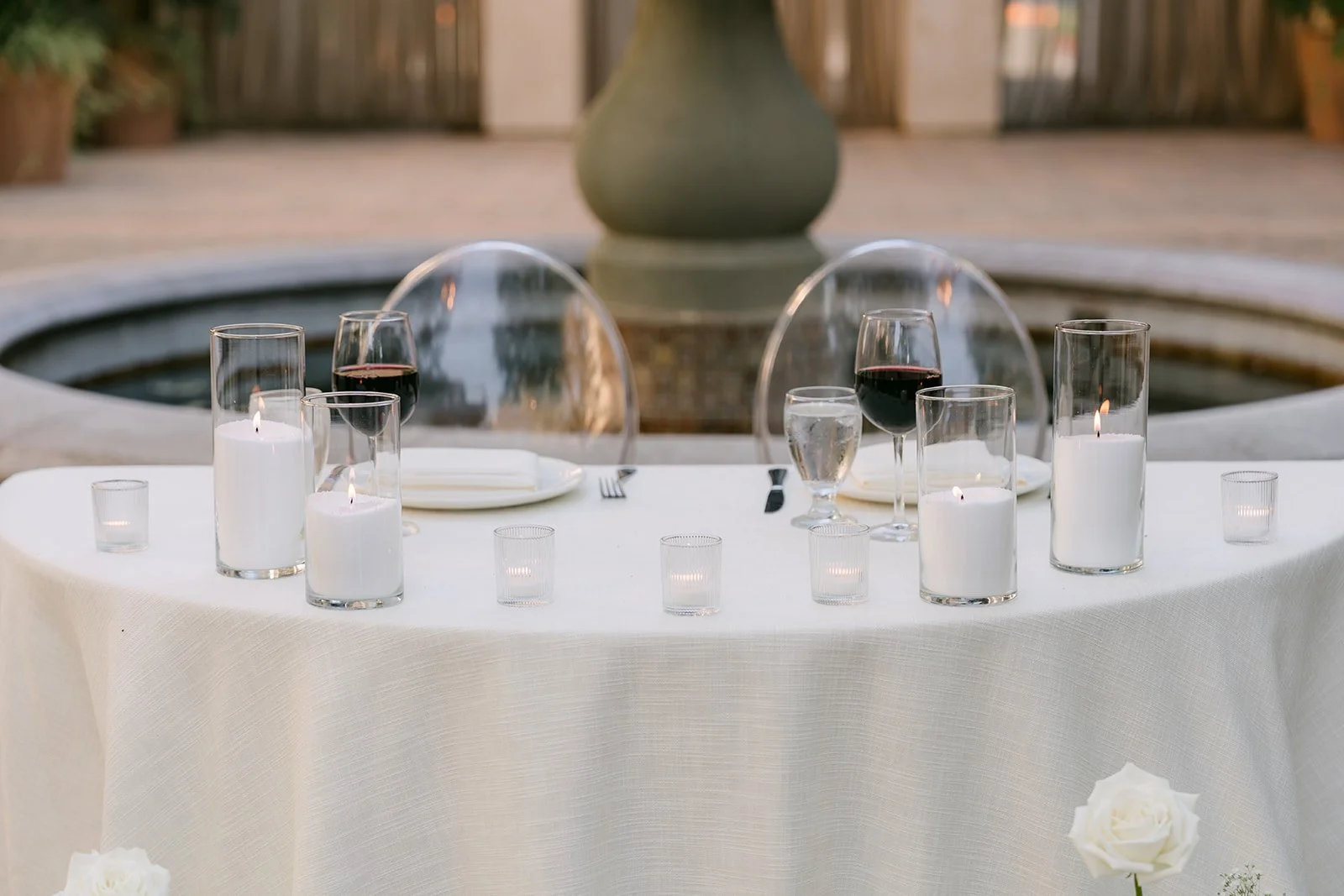 Round table with glass cloches and candles beside the fountain