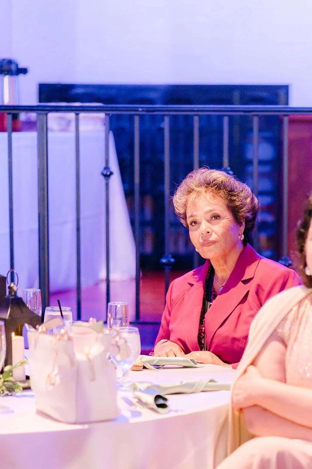 A guest smiling at her table during dinner, photographed by One and Only Production