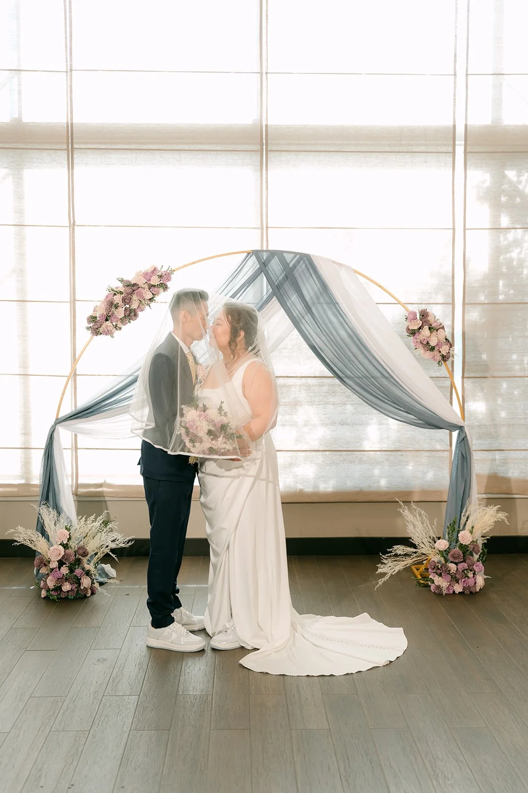 Mai and Bobby under the draped arch in front of the windows.