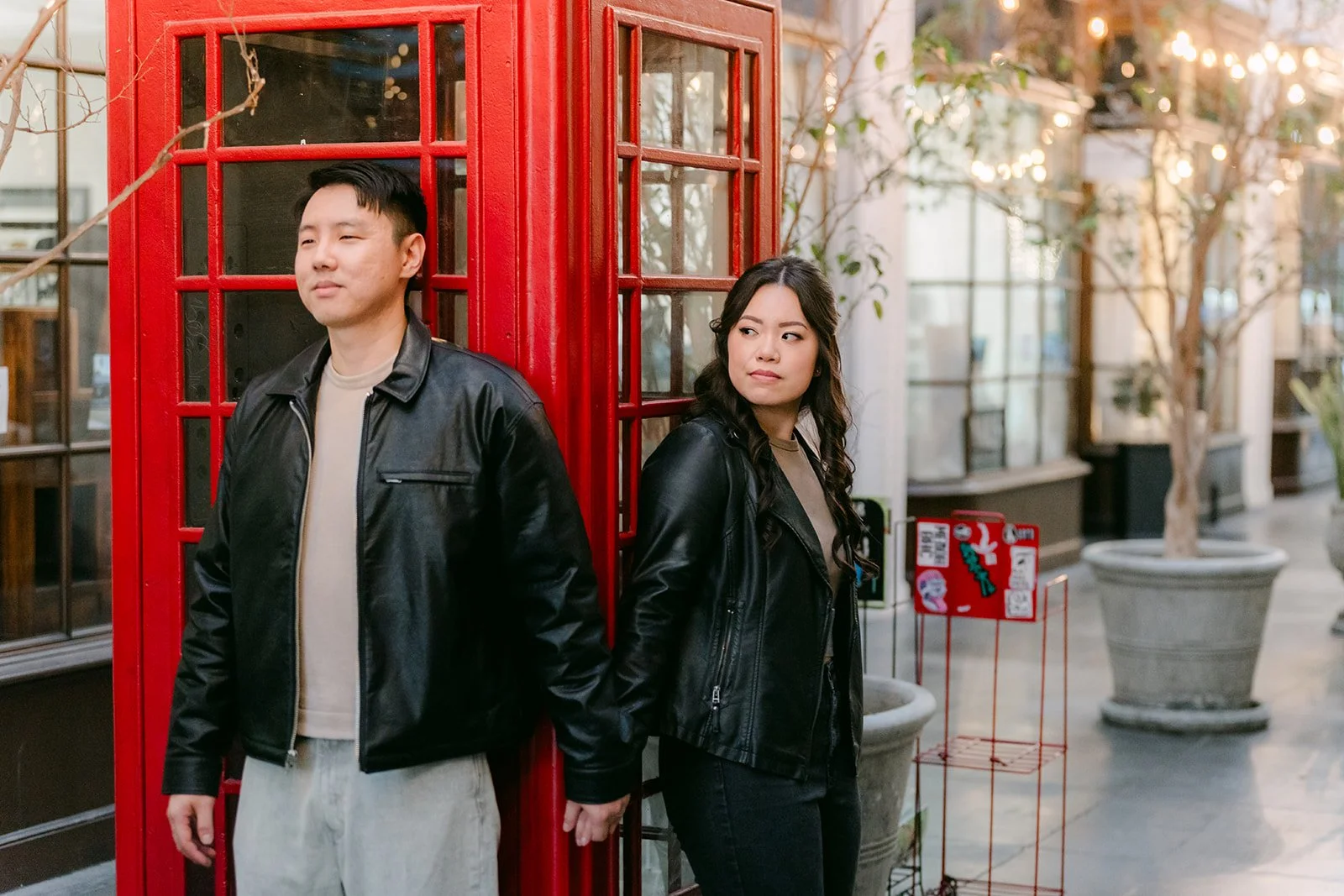 Emily and James pose inside the red phone booth at the Burlington Arcade.