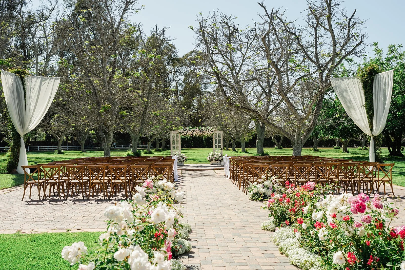 Ceremony site with draped arch and pink and white roses