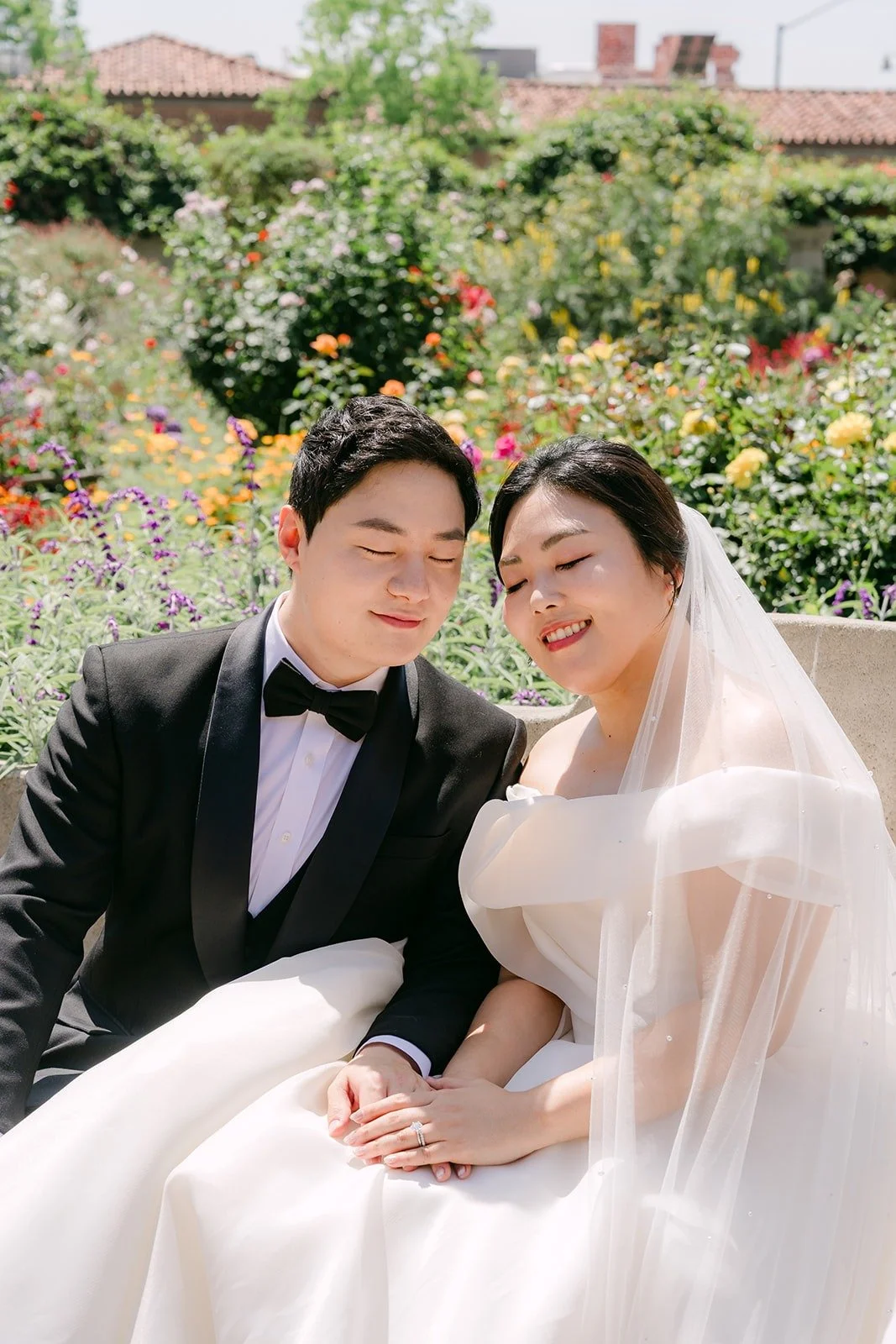 Chorok and Min Soo sitting together in front of a flower bed at the Mission