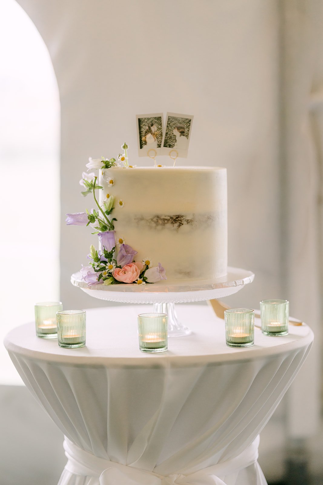 Two tier wedding cake with pastel florals and a custom topper