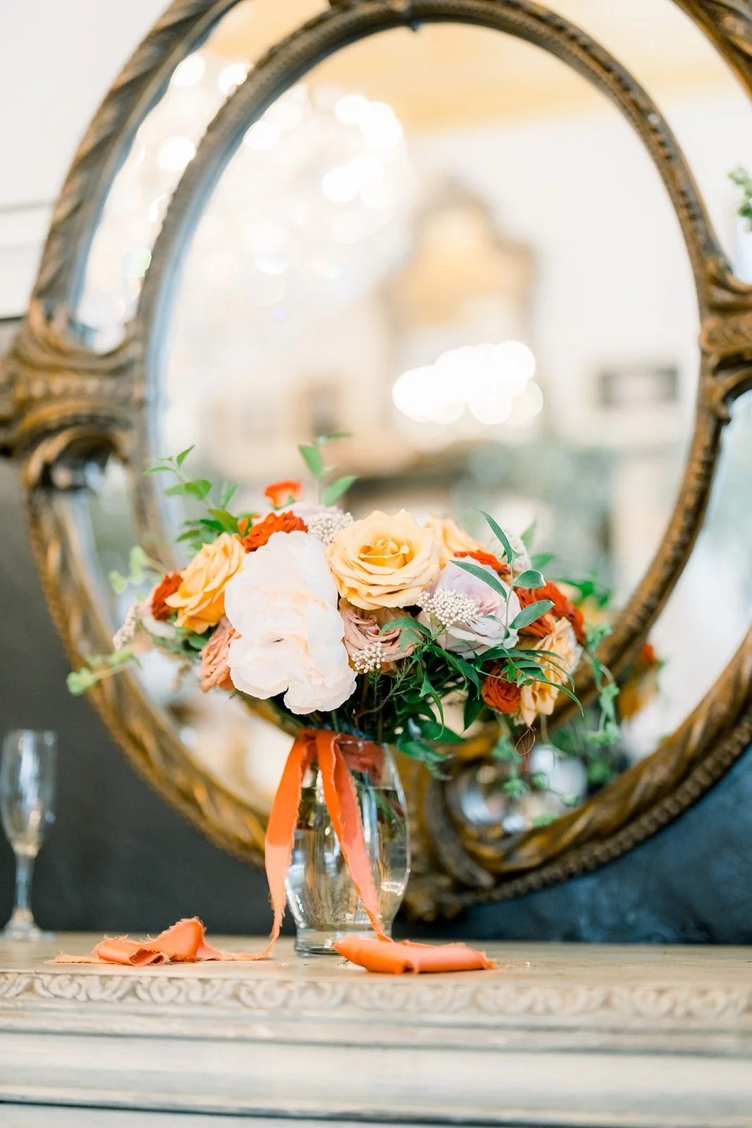 Hannah's peach and blush bouquet in front of an ornate gold mirror