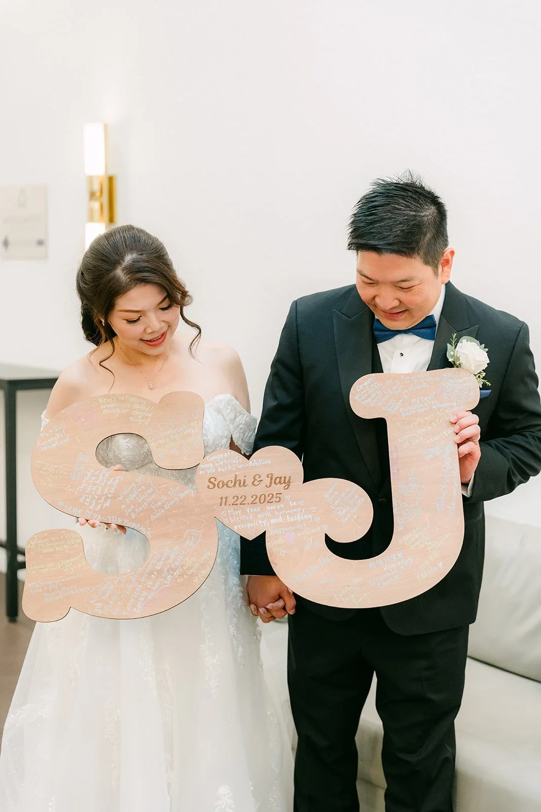 Sochi and Jay hold up wooden S and J letters before the grand entrance