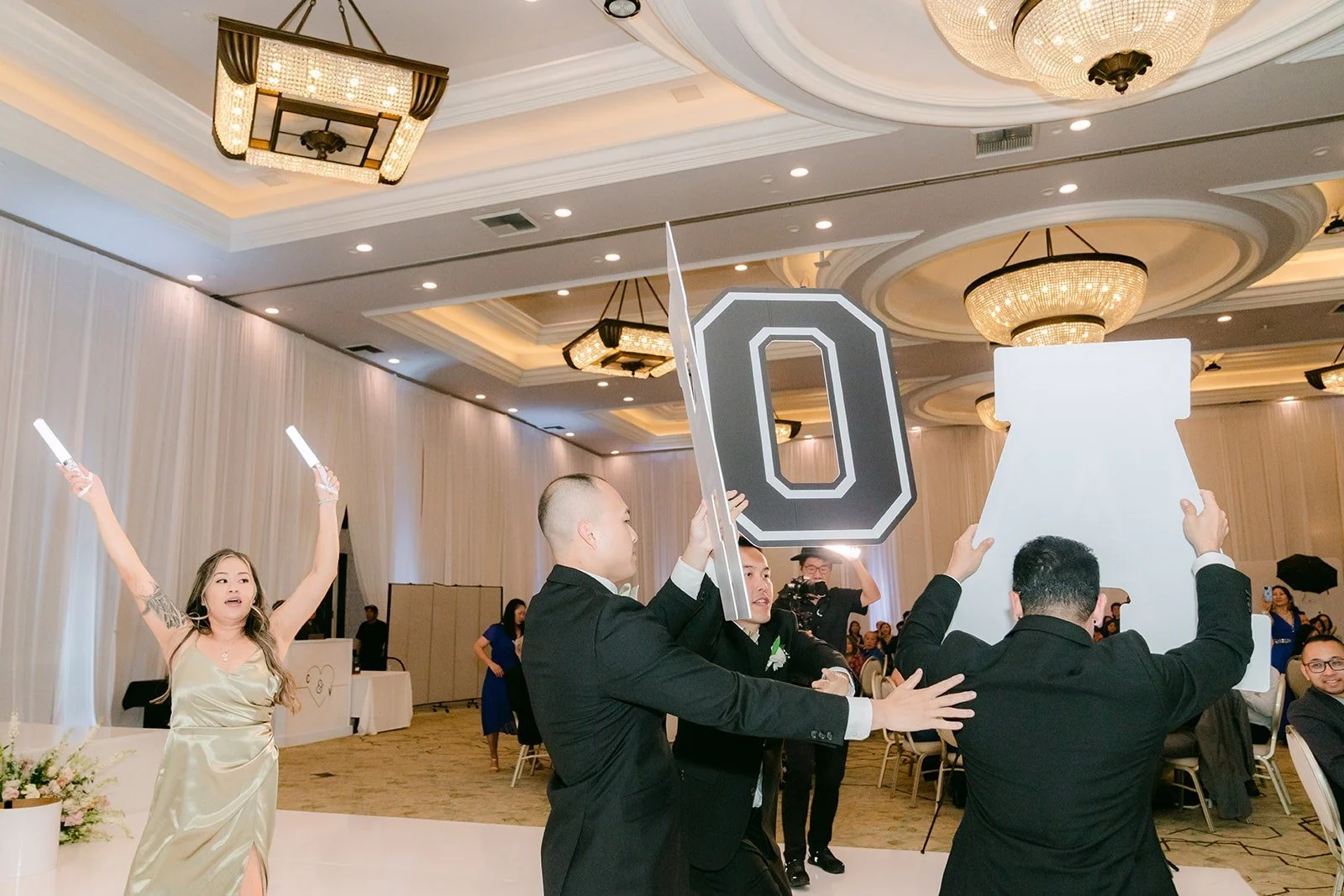Bridesmaids and groomsmen spelling out HOANG on the dance floor