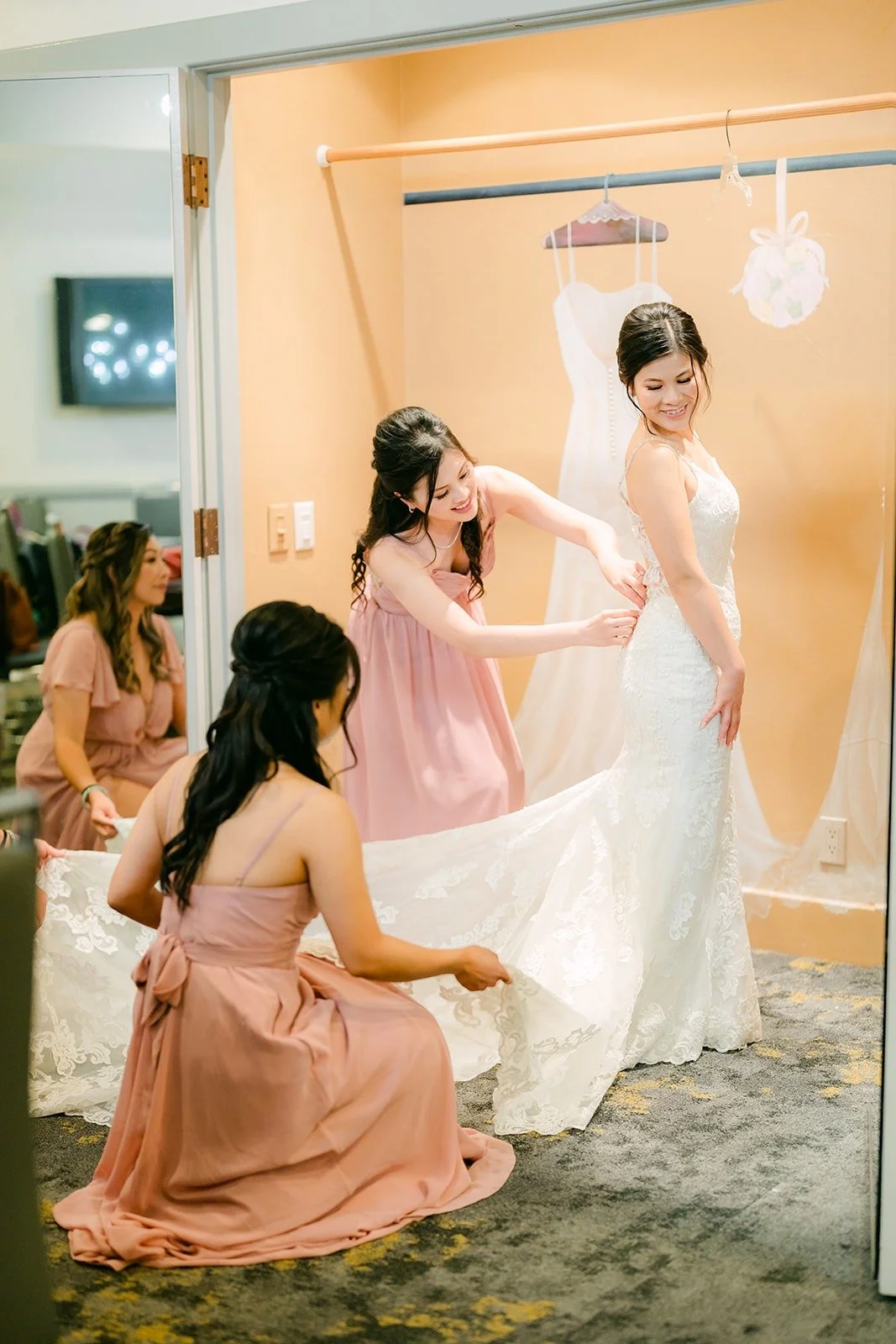 A bridesmaid in blush fastening Xuemin's gown