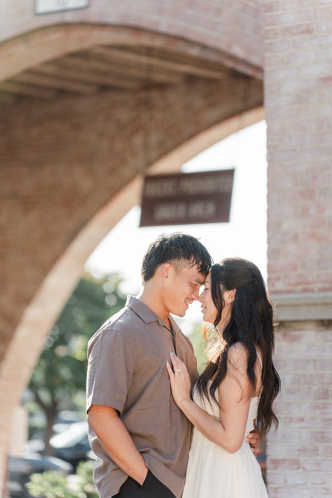 Andrew and Victoria share a quiet moment under a brick arch near the fountain.