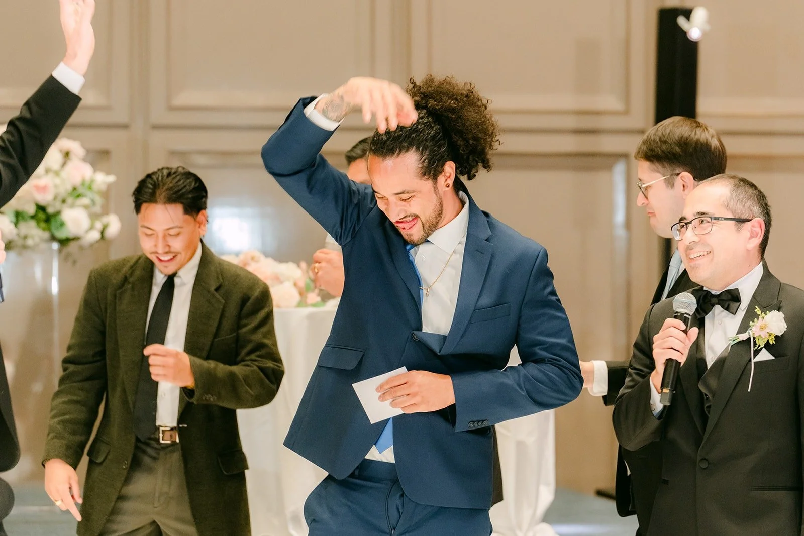 A guest dancing during a reception game as the groomsmen laugh