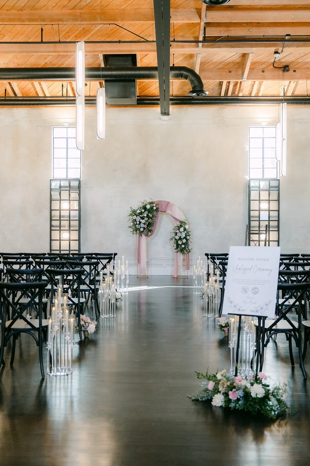 Rows of black chairs lead to the floral arch in the ceremony space at The Headquarters