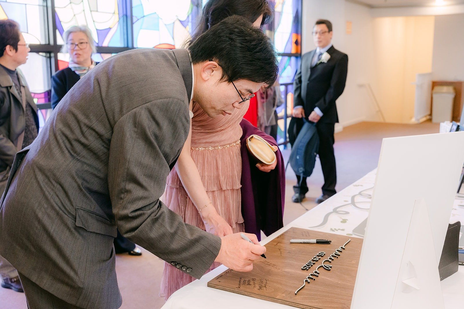 A guest signs the wooden guest book before the ceremony, photographed by One and Only Production