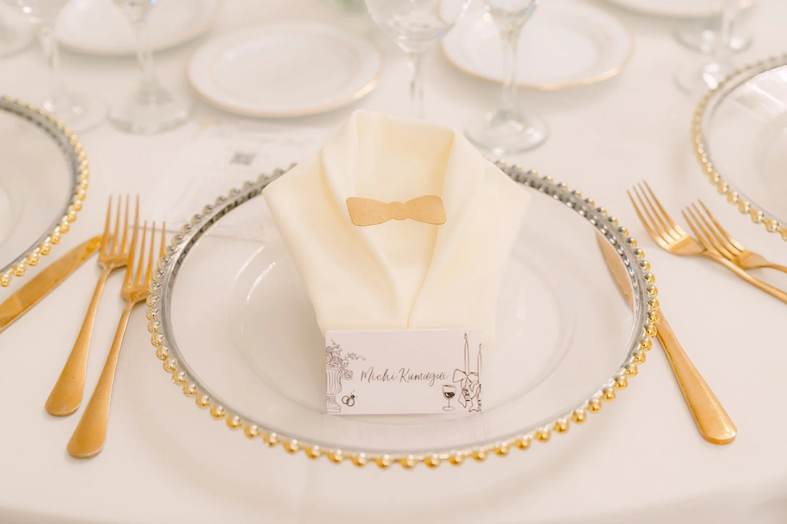 Gold rimmed charger, folded napkin and name card at Jenny and Ryan's reception.