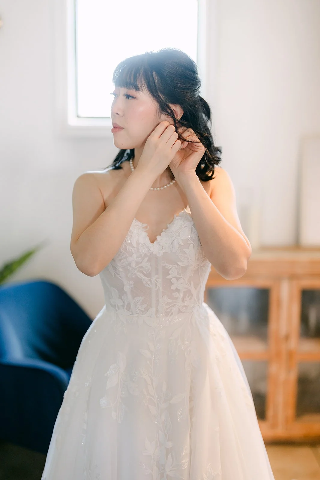 Vivian putting on her earrings by the window