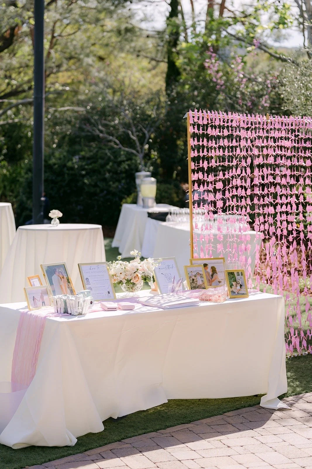 The welcome table with framed photos in front of a curtain of pink paper cranes