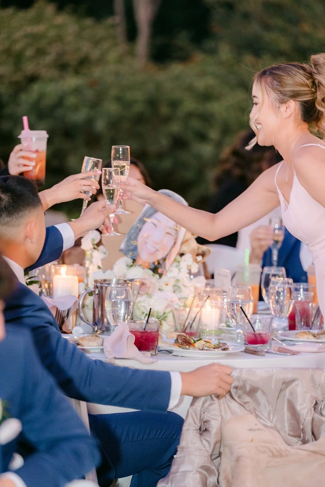 A bridesmaid raising her glass toward the sweetheart table